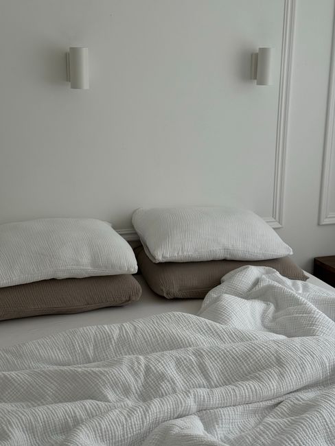 A cozy, minimalist bedroom featuring soft pillows and a white bedspread.