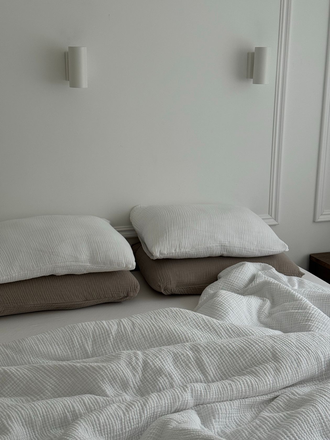 Layered bedding with a soft throw on a small cozy bed.