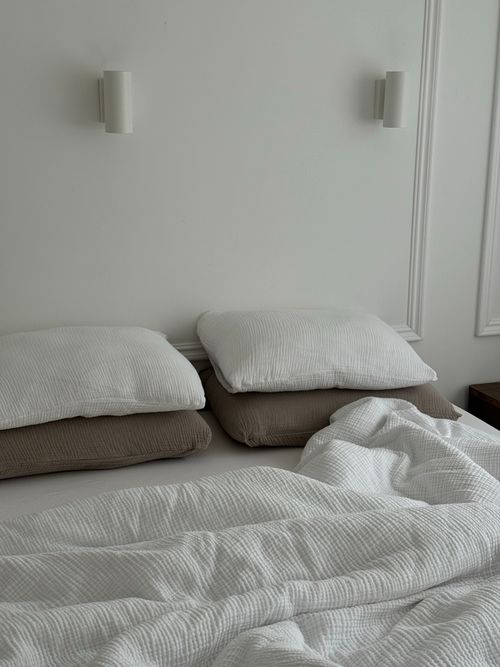 Free A cozy, minimalist bedroom featuring soft pillows and a white bedspread. Stock Photo