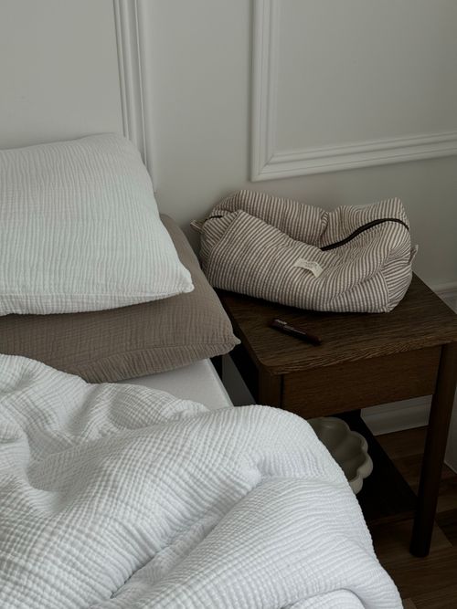 Free Simple bedroom setup featuring a bed, pillows, and a wooden nightstand with soft lighting. Stock Photo