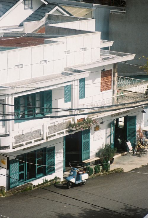 Free Vintage building with green shutters and a parked Vespa scooter on a sunny day. Stock Photo