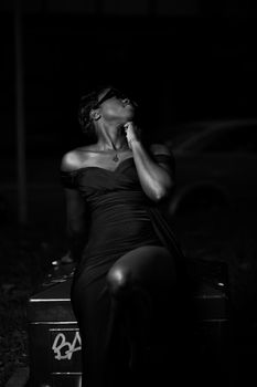 Dramatic black and white portrait of a woman in elegant attire at night.