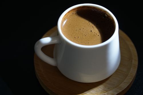 Free Close-up shot of traditional Turkish coffee served in a white cup on a wooden coaster. Stock Photo