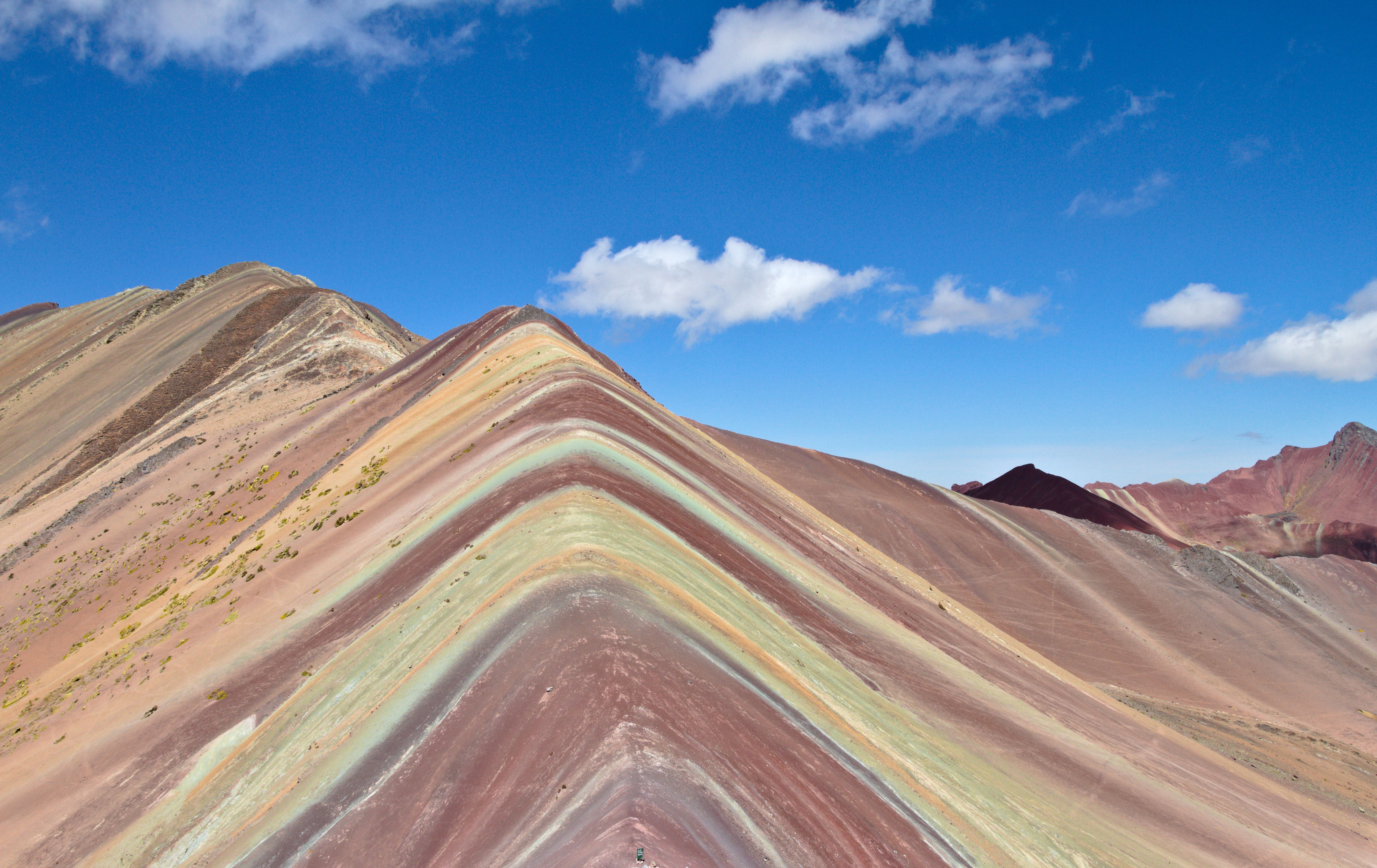 Stunning aerial view of Rainbow Mountain showcasing vibrant natural colors under a clear blue sky.