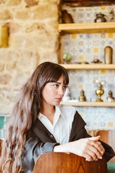 Portrait of a young woman seated in a cozy café with vintage decor.
