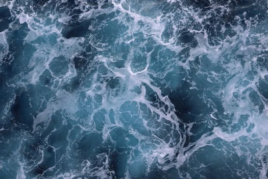 Dynamic aerial shot capturing the movement of ocean waves with foamy textures.