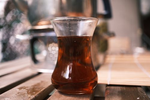 Free Close-up of traditional Turkish tea glass with rich tea on a wooden table, capturing a cozy ambiance. Stock Photo