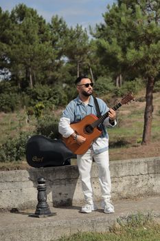 Casual scene of a man playing an acoustic guitar in a sunny park.