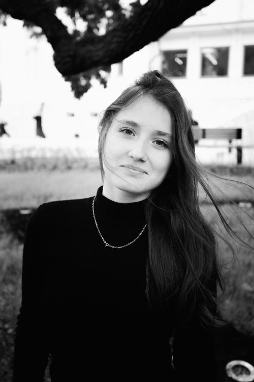Free A captivating black and white portrait of a young woman in a natural outdoor setting. Stock Photo