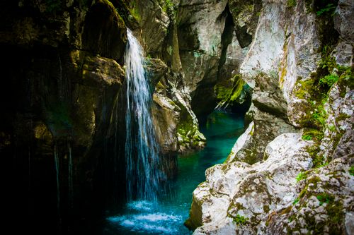 Free Discover the tranquil beauty of a waterfall cascading through moss-covered rocks in Slovenia's lush landscape. Stock Photo