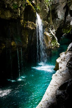 宁静的瀑布倾泻而下，落入峡谷中碧绿的水池，四周环绕着长满苔藓的岩石