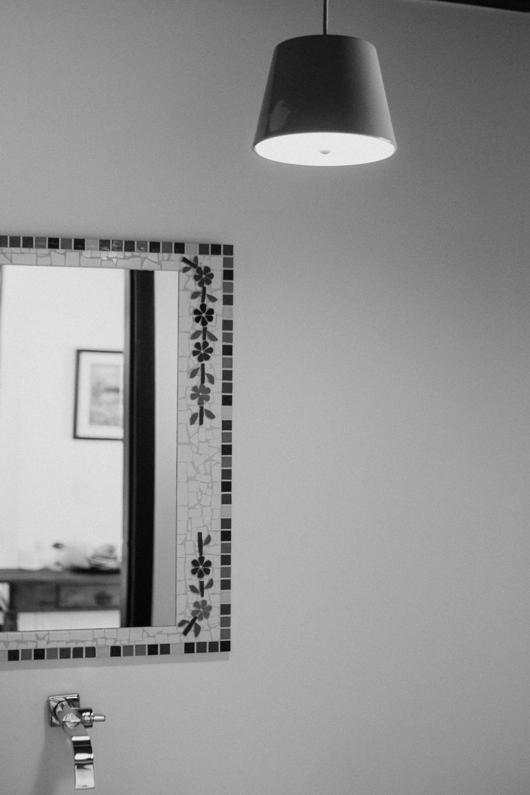 Black-and-white bathroom with decorative geometric tile around a wall mirror