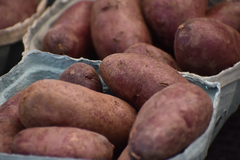 Close-up of fresh sweet potatoes displayed in rustic market baskets at a local farmers market.