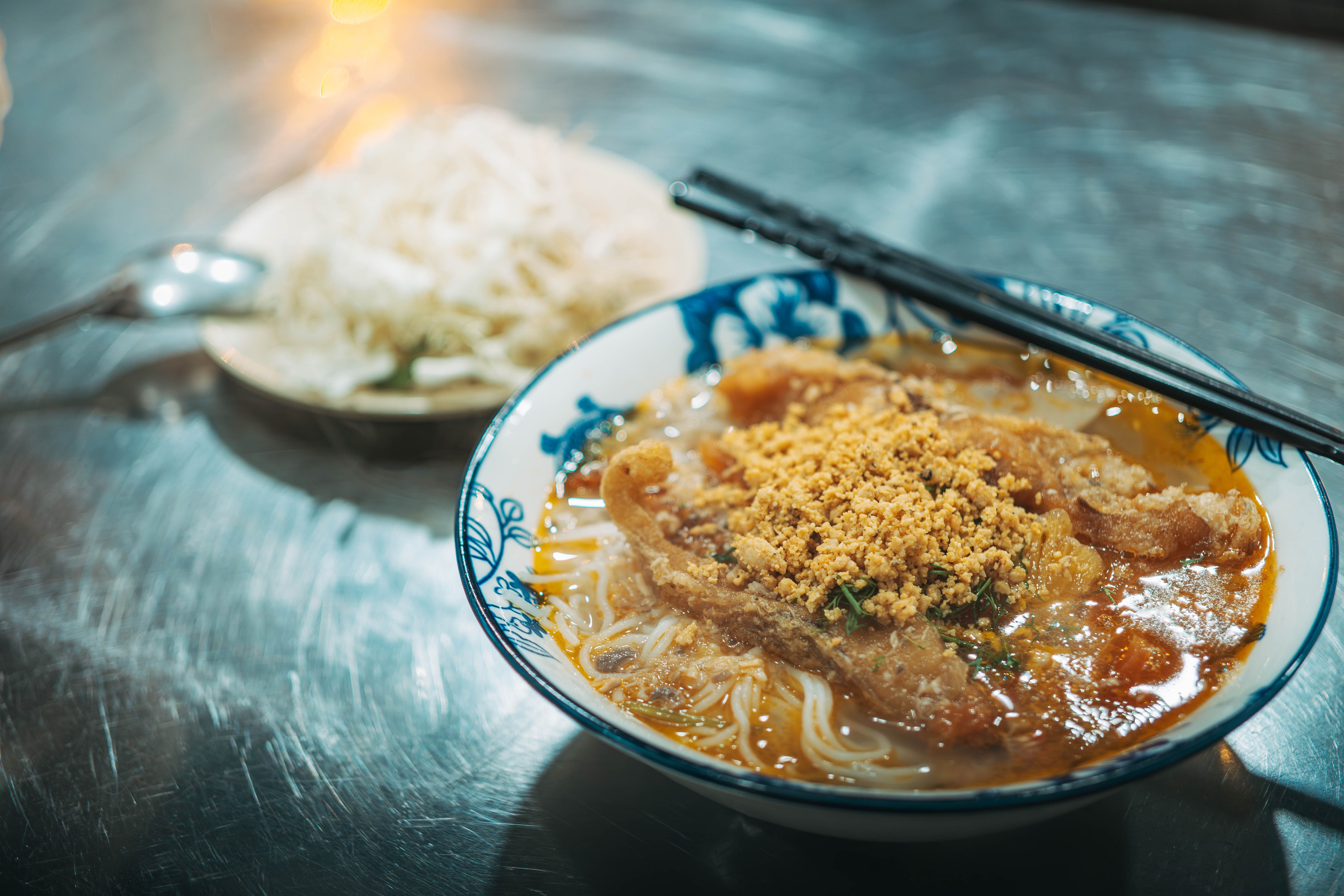 Appetizing Asian noodle soup with crispy topping served in a floral bowl, perfect for authentic food lovers.