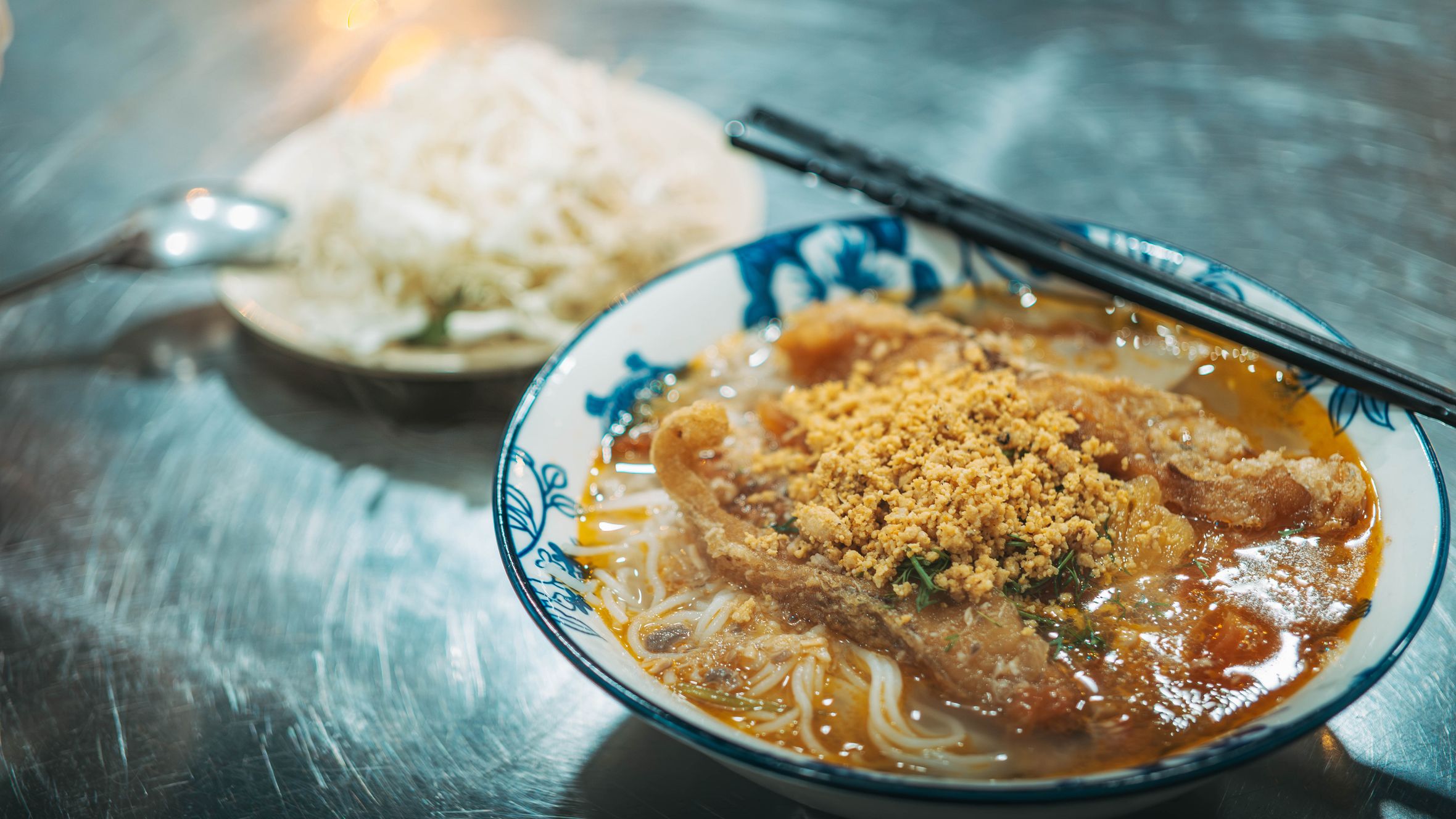 Appetizing Asian noodle soup with crispy topping served in a floral bowl, perfect for authentic food lovers.