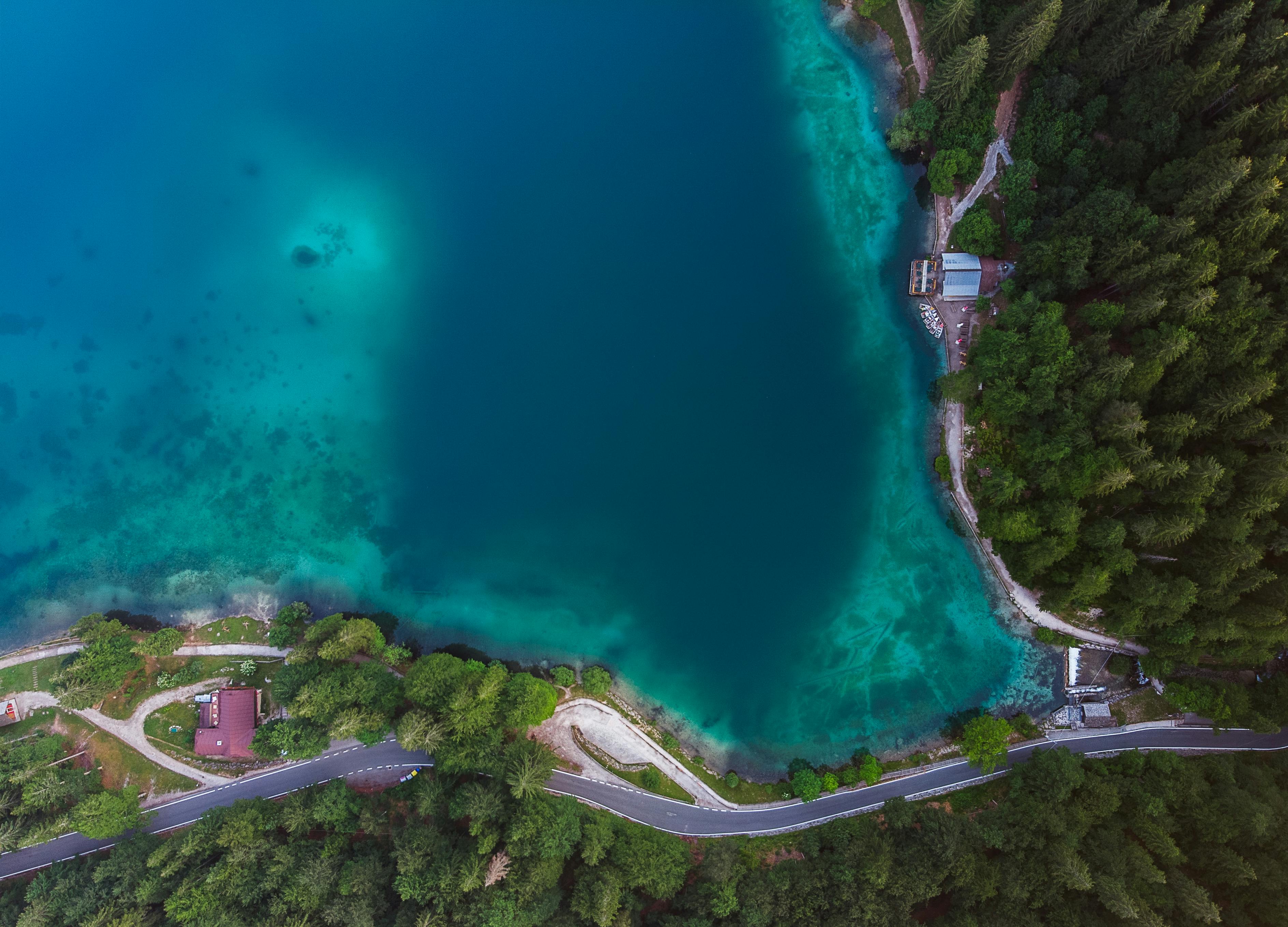 从令人惊叹的鸟瞰视角看去，一个宁静的森林湖被郁郁葱葱的绿色植物和蜿蜒的道路环绕着