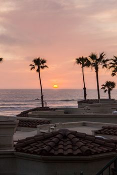 Stunning sunset view over Oceanside beach, highlighting palm trees against a serene ocean backdrop.