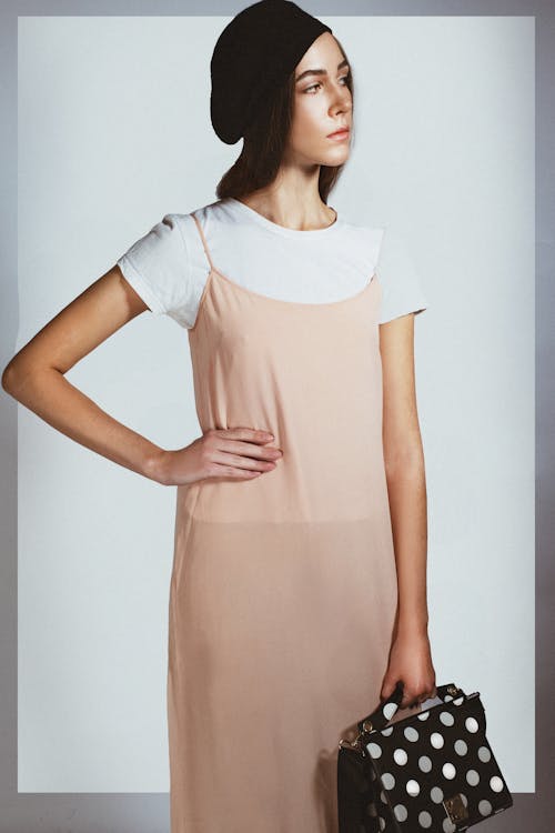 Photo of a Model in a Beige Dress Posing with Her Hand on Her Waist