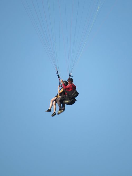 Free Enjoy the thrill of tandem paragliding against a clear blue sky, perfect for adventure seekers. Stock Photo