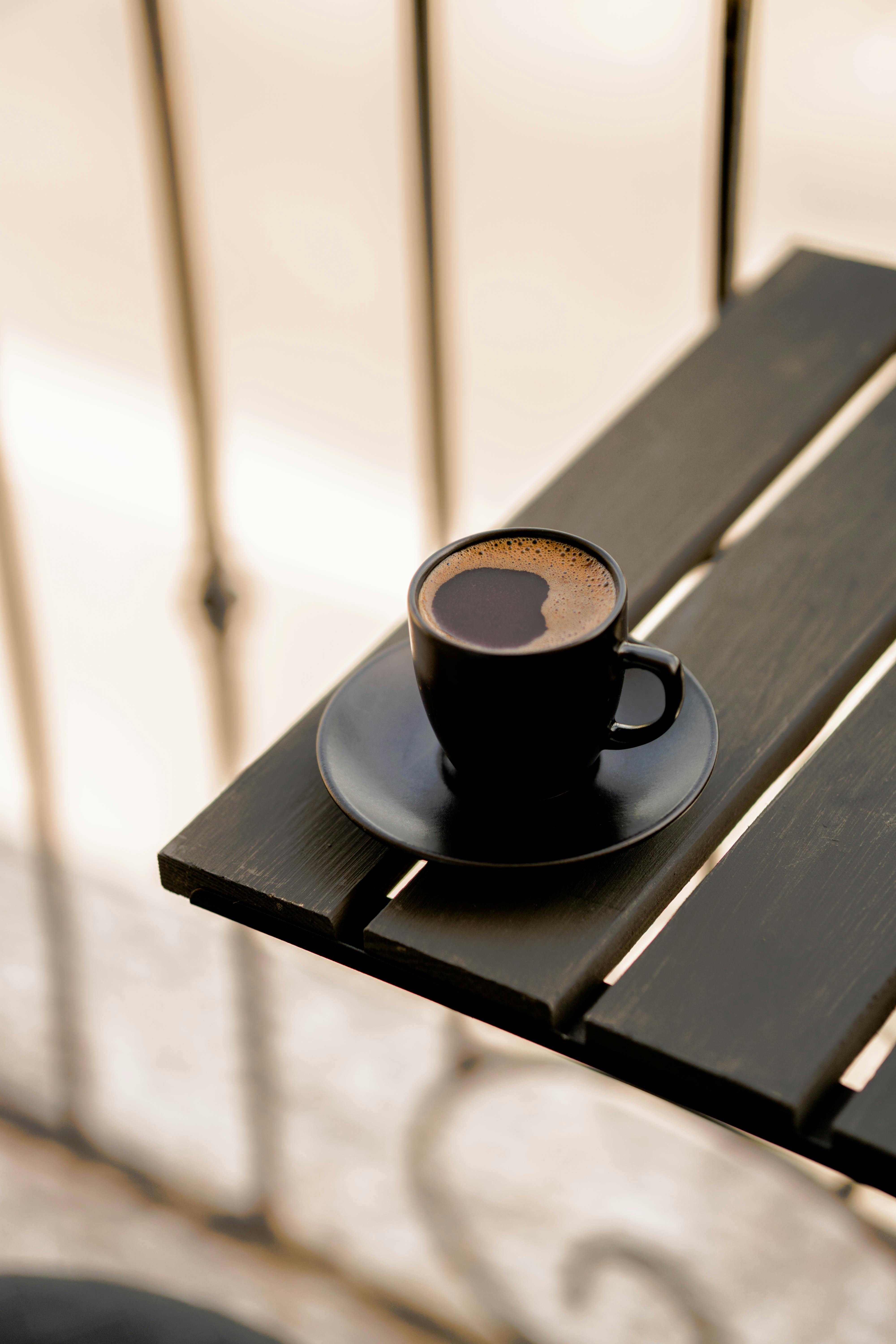 A Woman Sitting on a Bench Holding a Coffee Paper Cup · Free Stock Photo