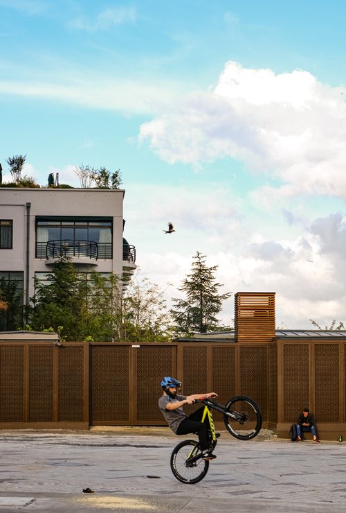 Free A cyclist performs an impressive stunt in front of a modern building in Istanbul, under a vibrant sky. Stock Photo
