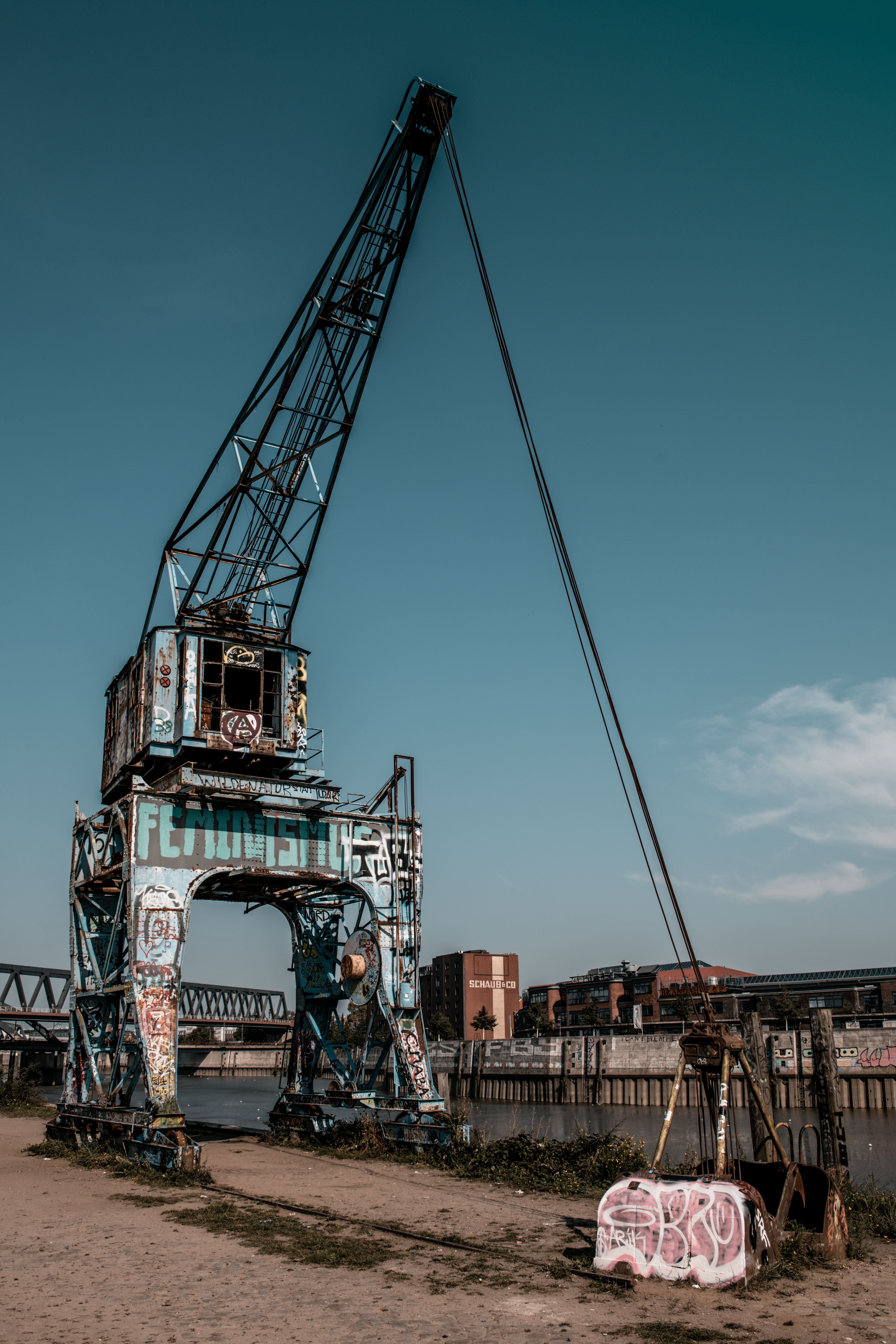 Vibrant graffiti on an old crane in Hamburg's scenic harbour area.