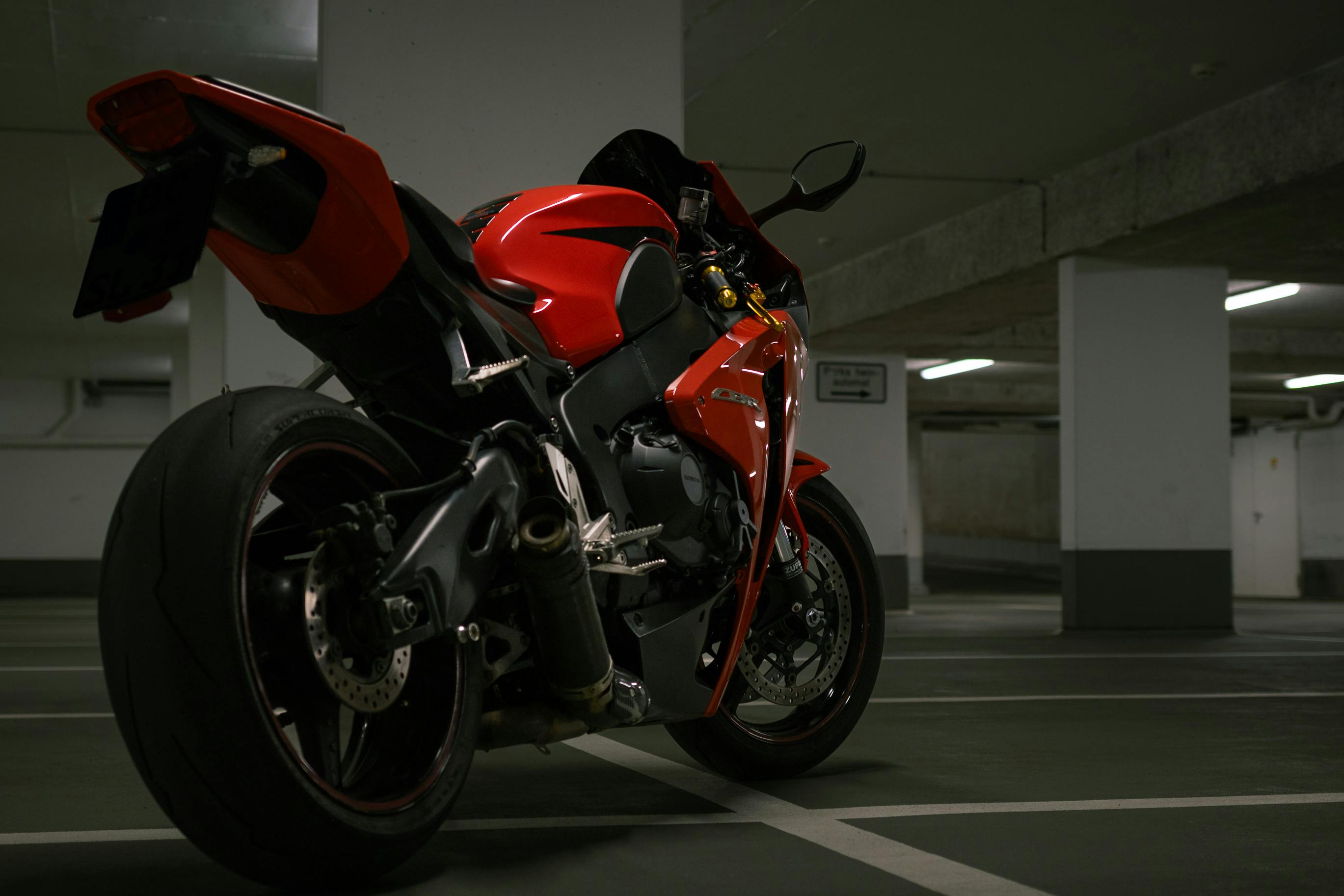A striking red superbike parked in a dimly lit urban garage, exuding power and speed.