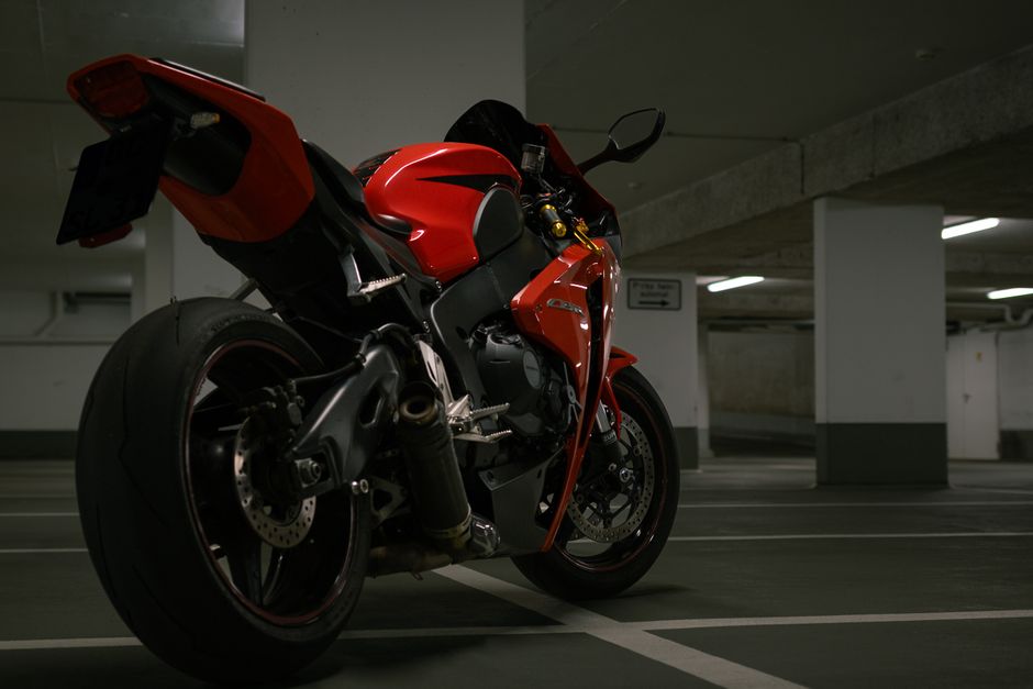 A striking red superbike parked in a dimly lit urban garage, exuding power and speed.