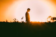 田野里站着一个人，背景是充满活力的日落