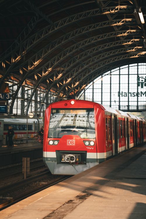 Free A red train arrives at Hamburg Hauptbahnhof, Germany, showcasing urban architecture. Stock Photo