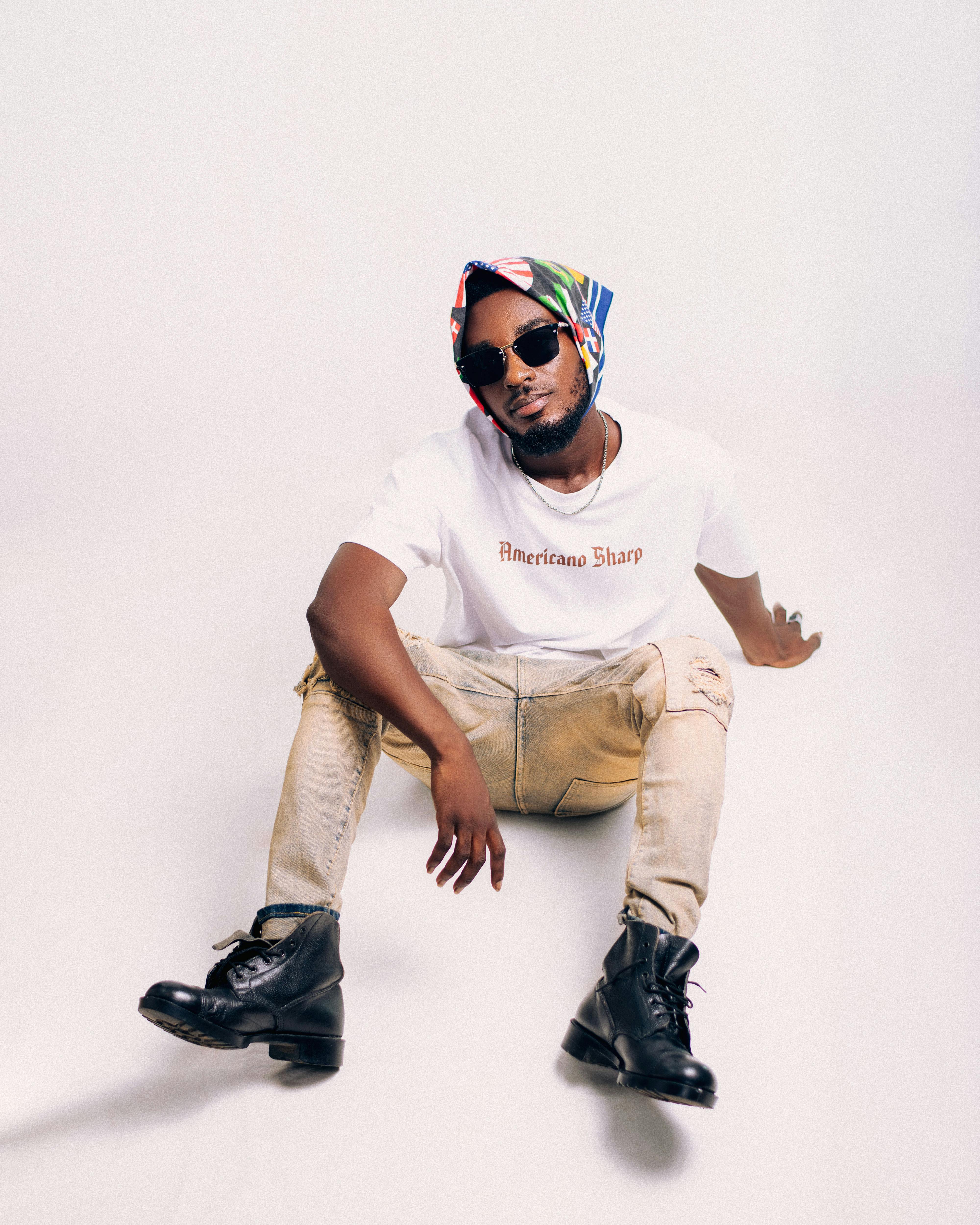 Fashionable man wearing a bandana and sunglasses, posed against a white backdrop.