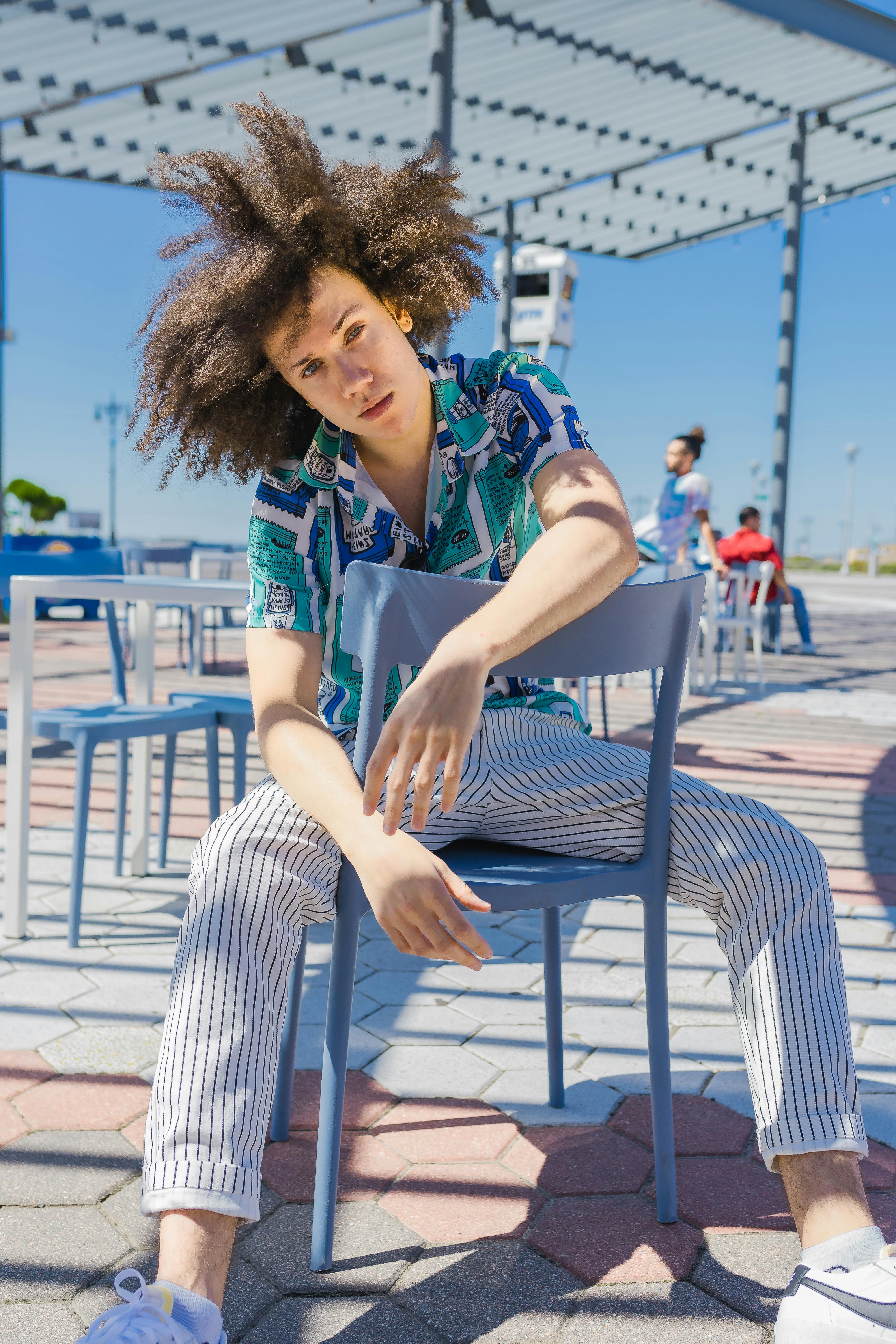 Trendy individual in a stylish attire posing outdoors under a modern pergola.