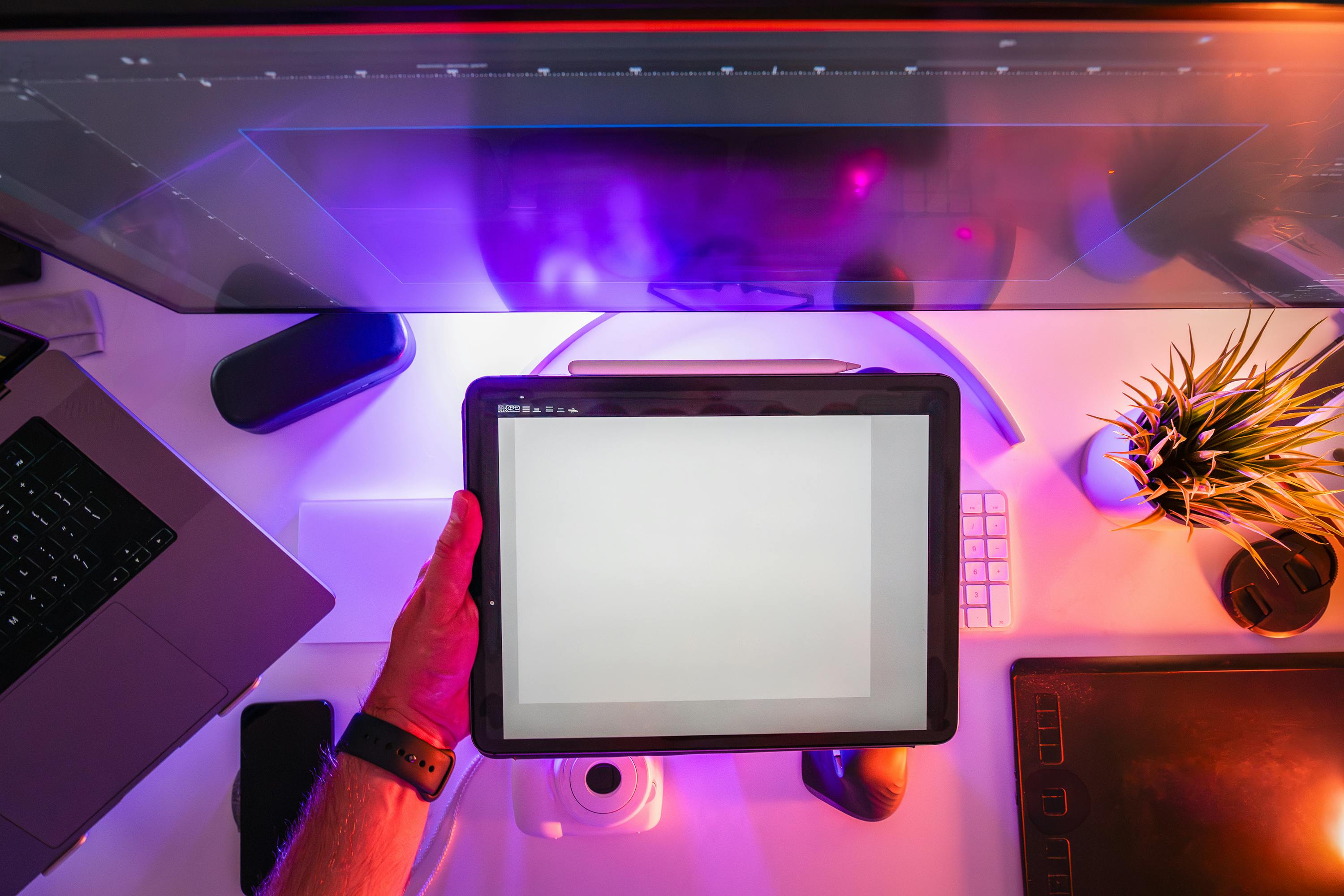 A vibrant workspace featuring a digital tablet and neon lighting, ideal for designers or photographers.