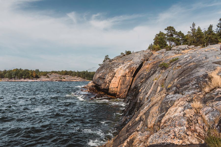 Scenic view of rugged cliffs and sea in Porkkala Peninsula, Finland, under a cloudy sky.