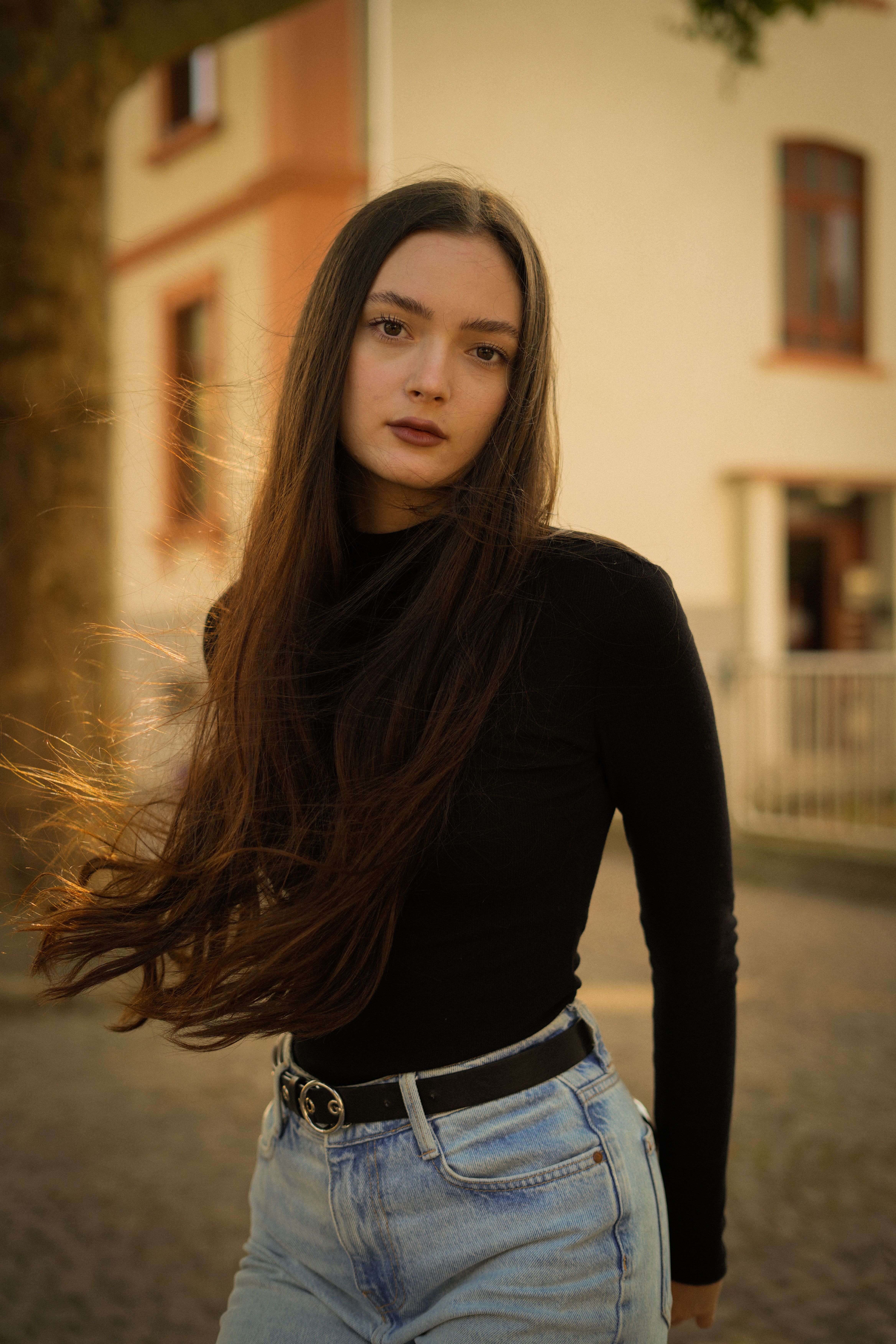 A fashionable young woman with long hair poses outdoors in Frankfurt, capturing autumn vibes.