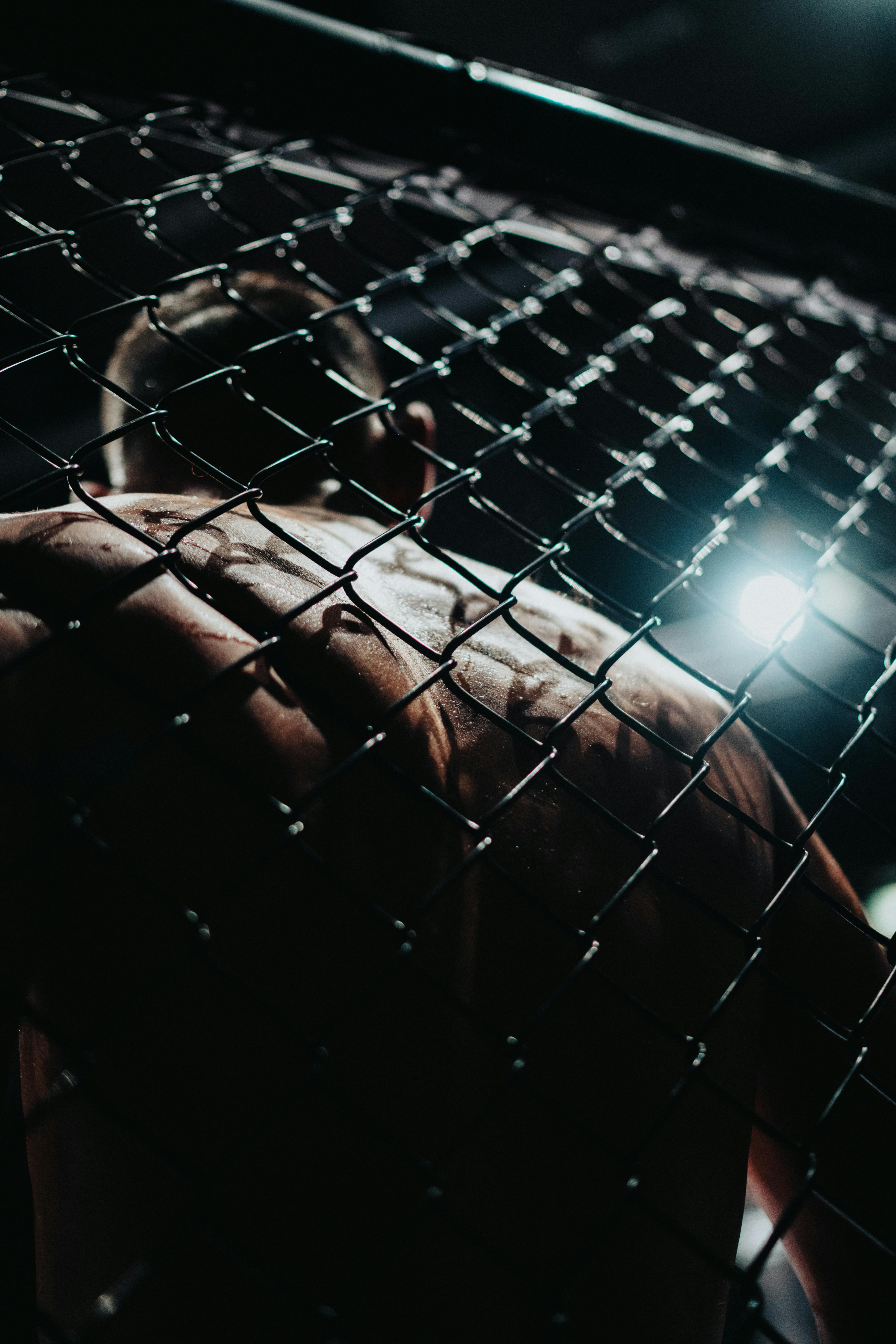 MMA fighter standing behind a cage fence