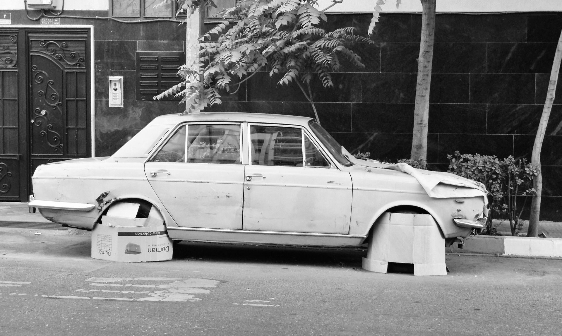 Old car parked on a Tehran street, showcasing urban decay.