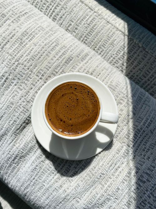 Free Rich Turkish coffee in a white cup casting shadows on a textured fabric. Stock Photo