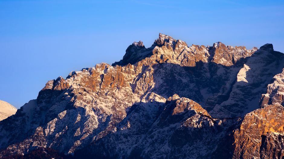 Breathtaking view of the snow-capped Dolomites in Italy during sunset, highlighting rugged peaks.