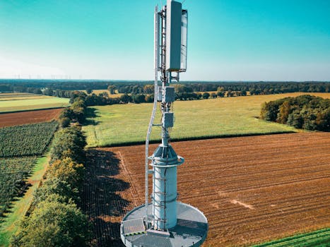 Aerial view of a cell tower amidst vibrant farmland, symbolizing technology and nature coexistence.