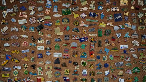 Free A diverse collection of vintage enamel pins displayed on a corkboard, showcasing unique designs and logos. Stock Photo