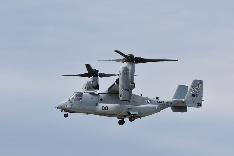 A V-22 Osprey military aircraft flying in a clear sky, showcasing its unique tiltrotor capability.