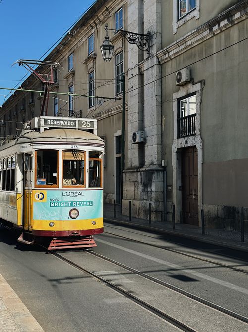 Free A classic tram travels through Lisbon's historic city streets on a sunny day. Stock Photo