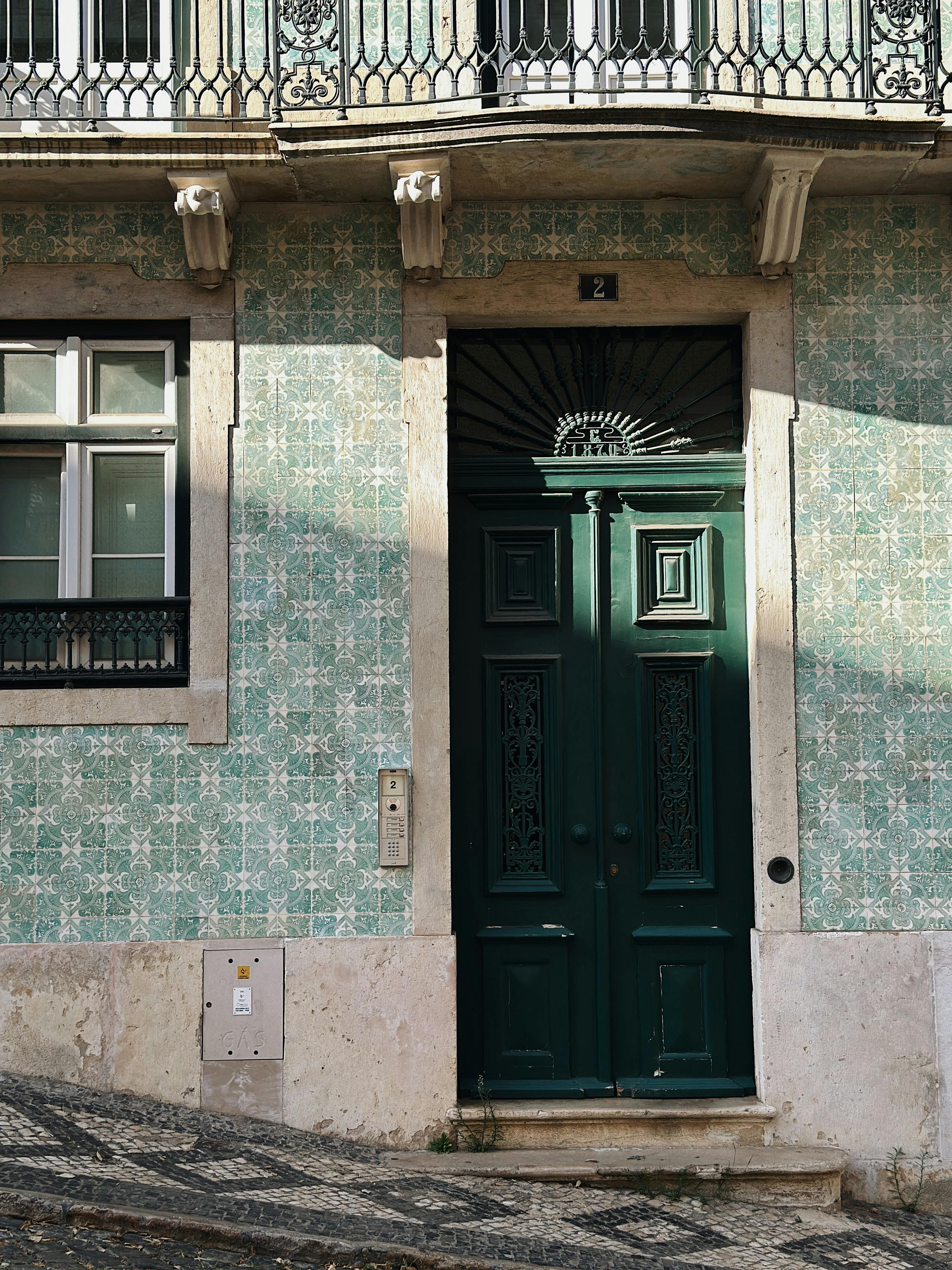 Charming Portuguese facade with green door and traditional tiles.