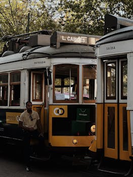 Charming yellow tram with a passenger at L. Camões station in Lisbon, Portugal.