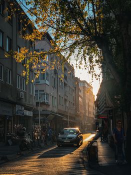 A serene evening street view in Balıkesir, Türkiye with golden sunlight filtering through the trees.