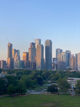Skyline view of Toronto during twilight with lush green parks in the foreground. Modern cityscape.