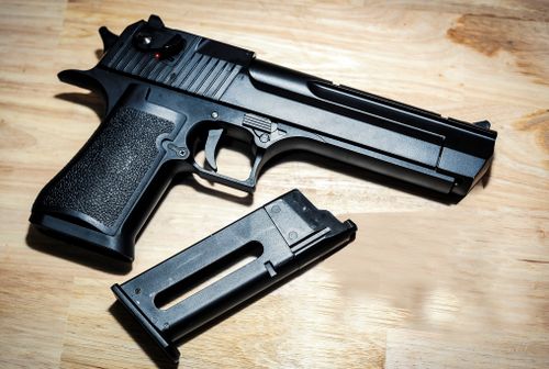 Free Close-up of a black pistol and magazine on a wooden surface, highlighting firearm detail. Stock Photo