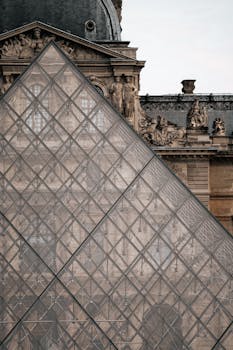 Louvre Museum's glass pyramid and historic facade in Paris, France.