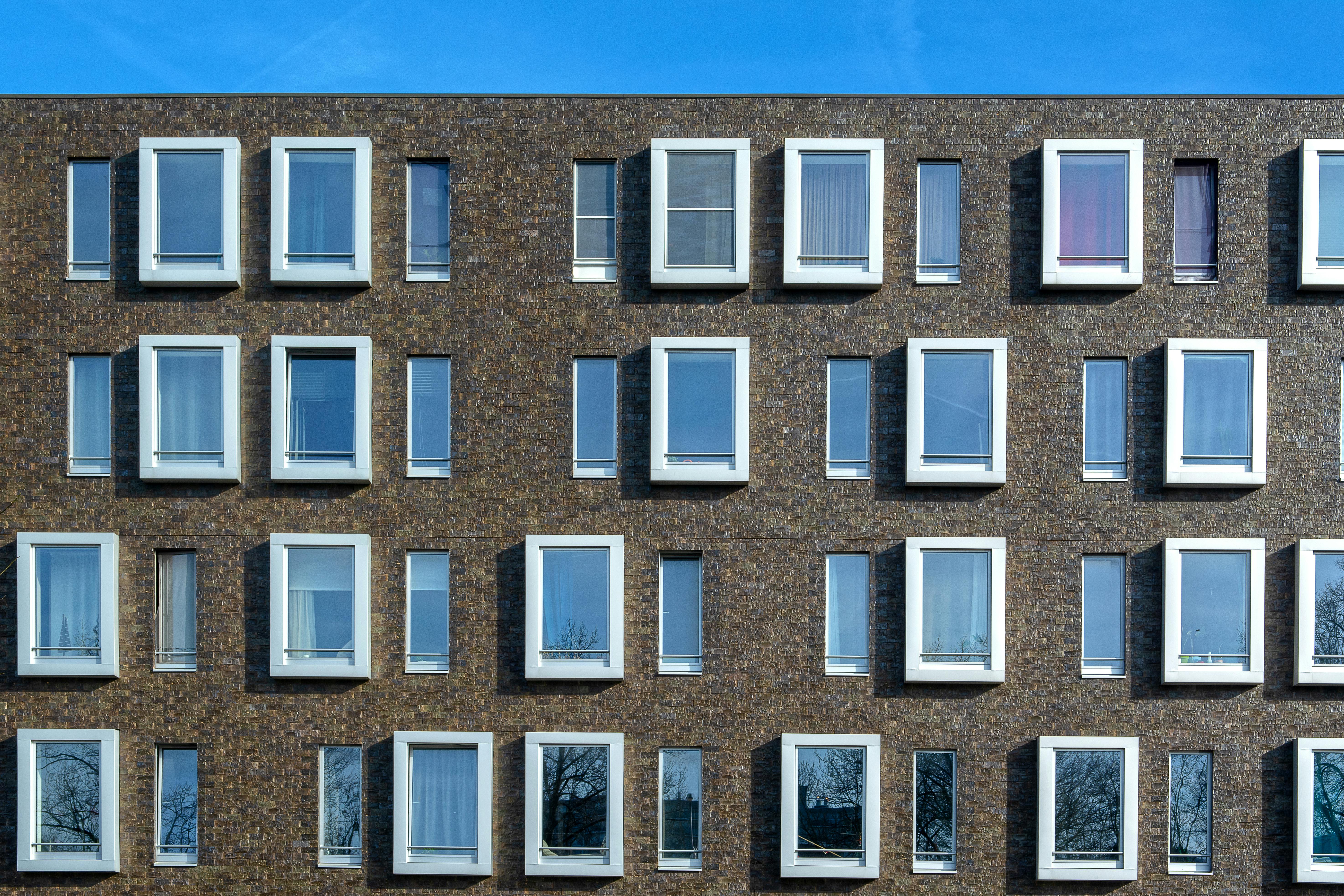 Contemporary building facade featuring symmetrical windows against a blue sky.